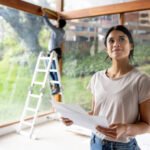 Latin American female architect renovating a house and holding designs at the construction site
